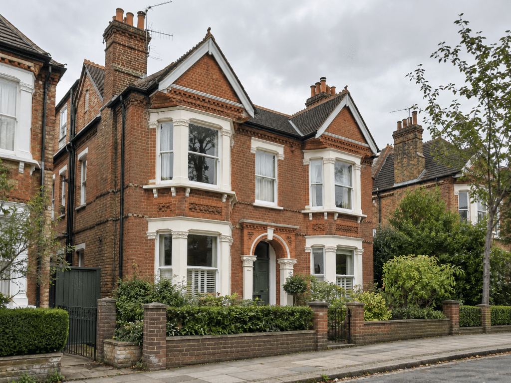Traditional Victorian red-brick house in the UK, featuring ornate architectural details, bay windows, pitched roofs, tall chimneys and a well-maintained front garden, illustrating historic residential architecture and ageing infrastructure.
