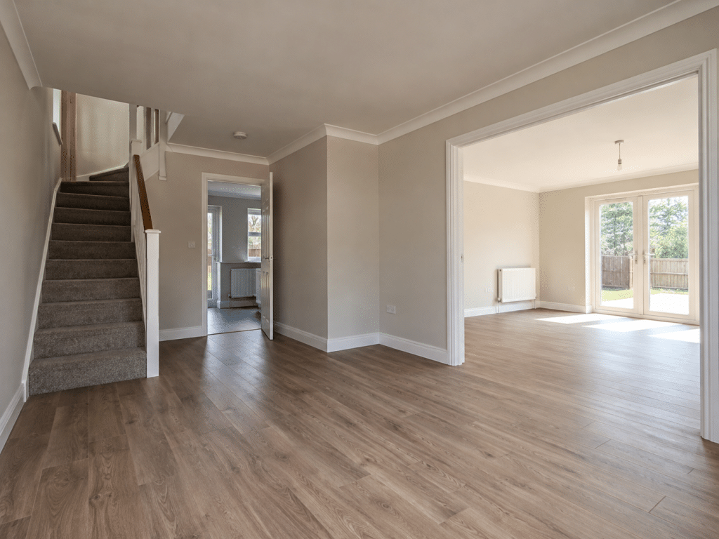 Empty modern home interior with bare rooms, wooden flooring, a staircase and natural light, representing a vacant residential property.