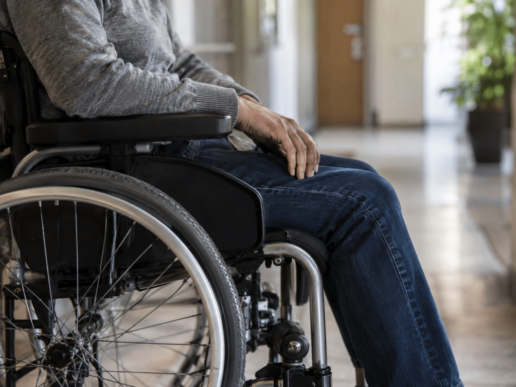 Close-up of a person seated in a wheelchair in a residential corridor, representing accessible fire evacuation planning and PEEPs.