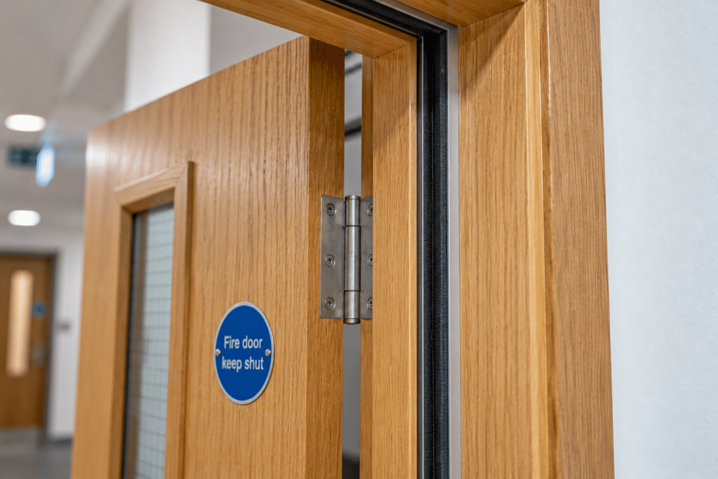 Close-up of a timber fire door showing a correctly fitted black intumescent smoke seal between the door leaf and frame.