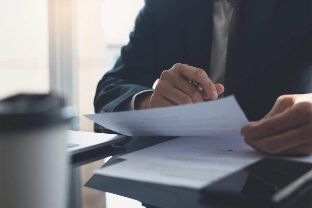 Closeup businessman reading before signing business contract documents