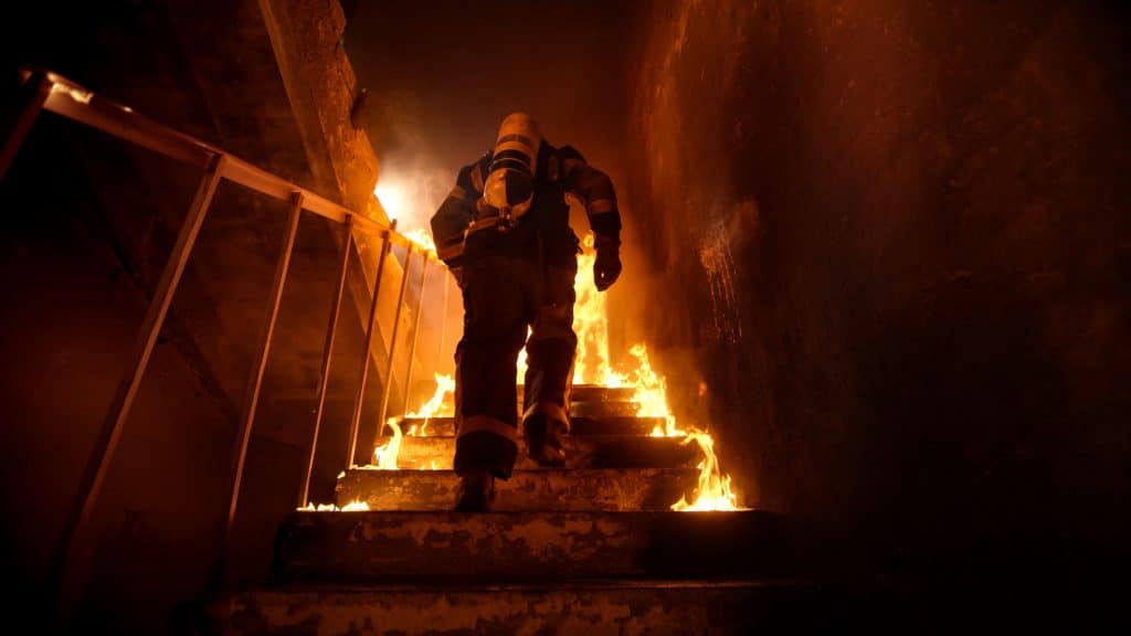 Strong and brave Firefighter Going Up The Stairs in Burning Building.,Stairs Burn With Open Flames.