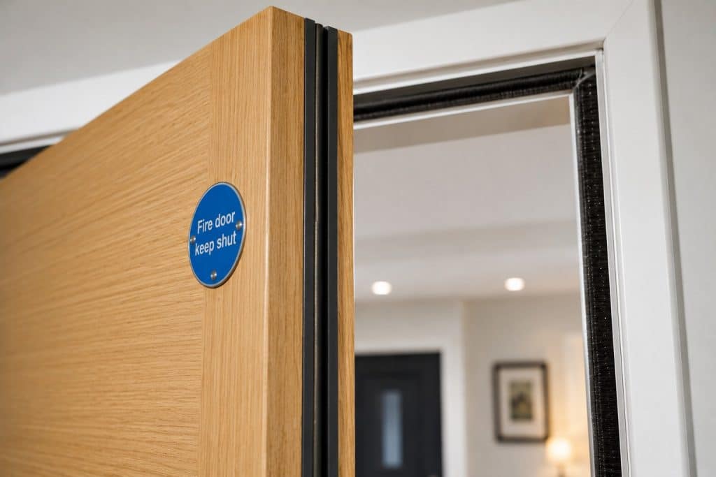 Wooden fire door slightly ajar showing smoke seals and fire seals